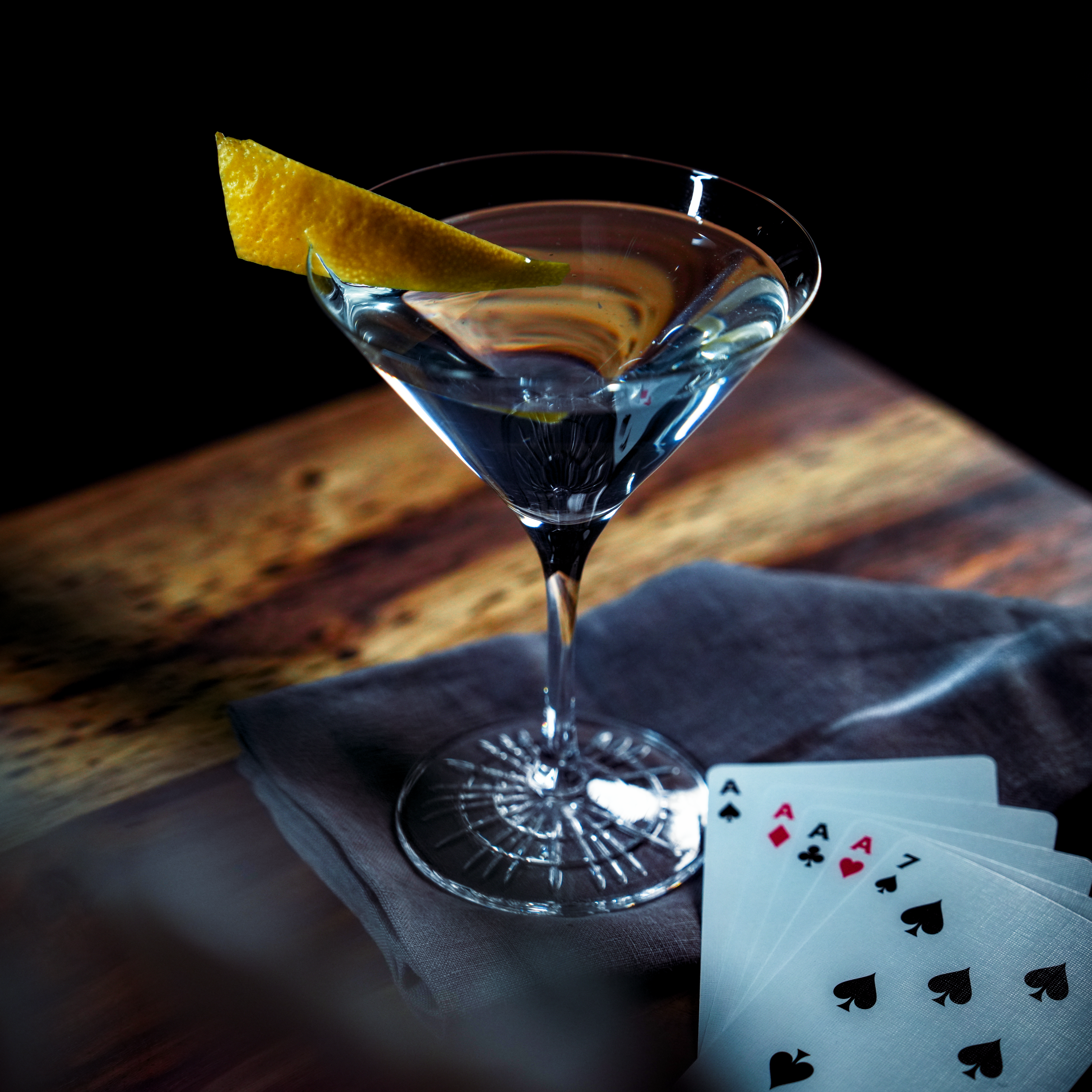 Martini Cocktail dekoriert mit einer Zitronenzeste, platziert mit Spielkarten auf einem Tisch